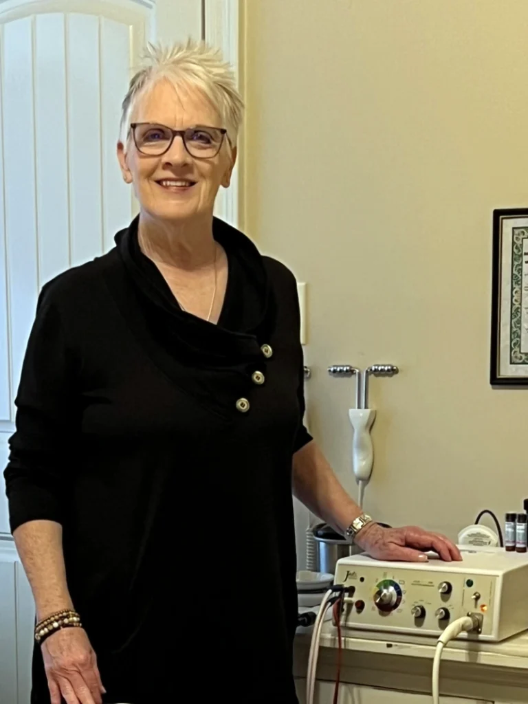 Dr. Betsy Goggan with Light Beam Generator for lymphatic therapy Dr. Betsy Goggan standing beside Light Beam Generator equipment in her naturopathic office in Lafayette, Louisiana