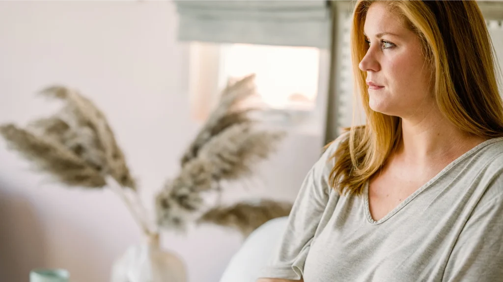Woman reflecting quietly in a cozy room, considering hair mineral analysis as part of her holistic health journey