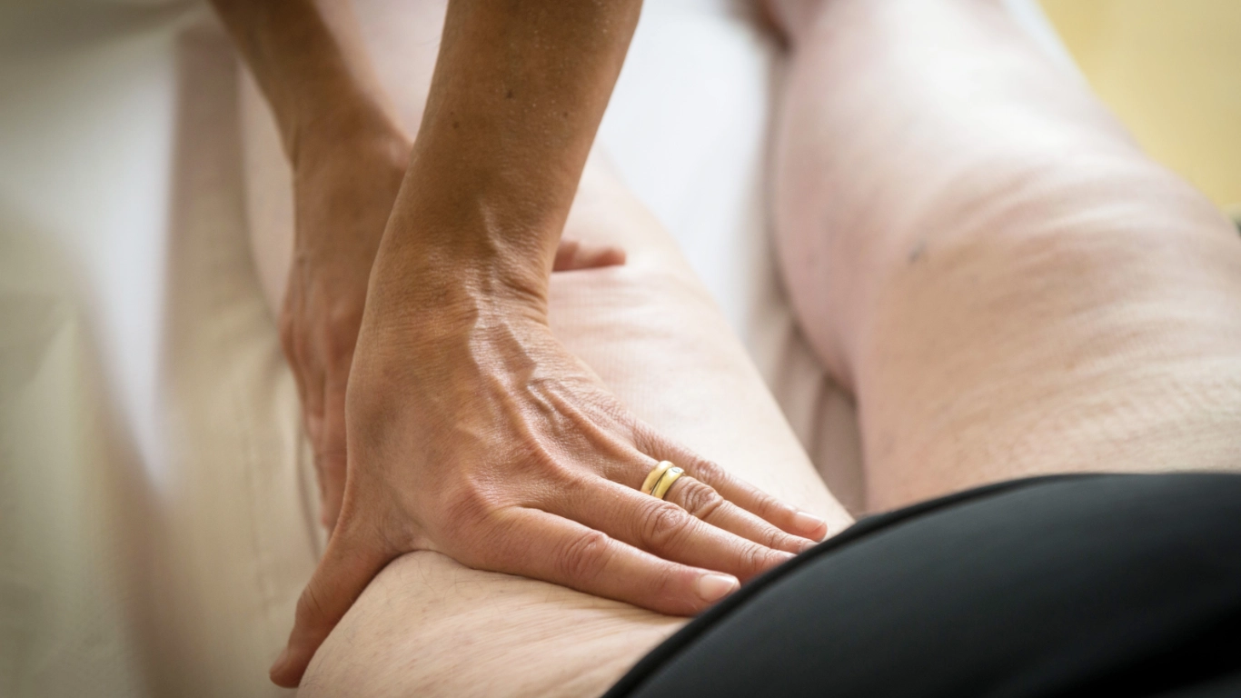 Close-up of a practitioner performing manual lymphatic drainage on a client’s leg—a gentle therapy used to support individuals with lymphatic system diseases.